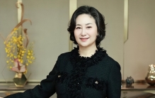 何超琼晚年发福明显，60岁近况状态好，与众人合影仍旧站C位